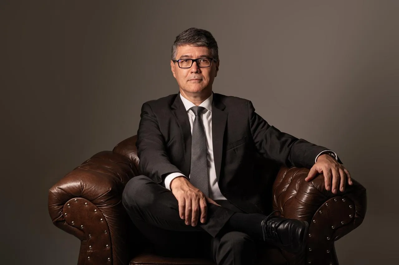 Dr. Nário Takimoto de terno, sentado em uma poltrona de couro